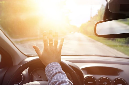 hand covering windshield from blinding sun